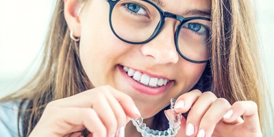 Young girl with glasses and earring holding ClearCorrect