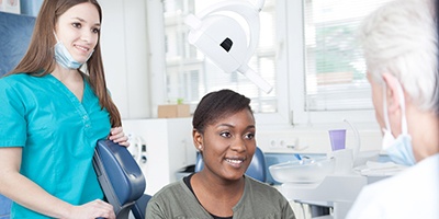 Implant dentist and dental assistant speaking with a patient.